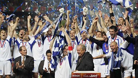 The Greek team cheering and celebrating with confetti in the background.