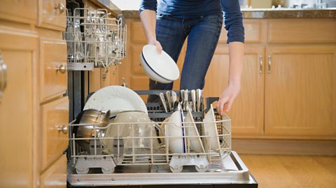 A woman putting dishes in a dishwasher.