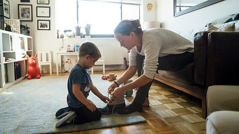 mother teaching her son how to tie his shoelaces