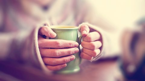 hand holding a mug of tea for warmth