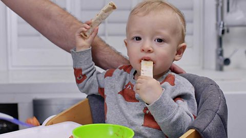 A baby boy with fingers of tortilla wrap.