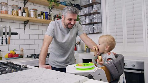 Miguel Barclay looking on at his son Charlie eating in a high chair