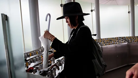 Getty Images A Japanese woman keeps her umbrella under lock and key in Tokyo's National Art Center (Credit: Getty Images)