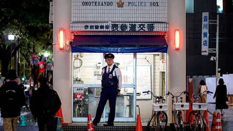 Getty Images A police officer stands guard outside a police box in Tokyo (Credit: Getty Images)