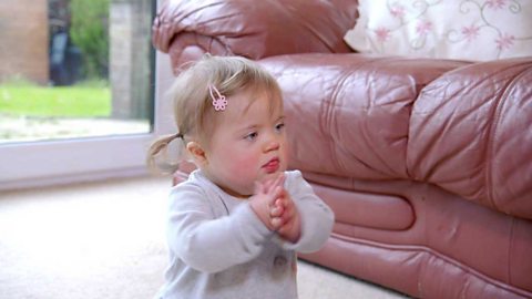 Toddler sat on floor doing nursery rhyme actions.