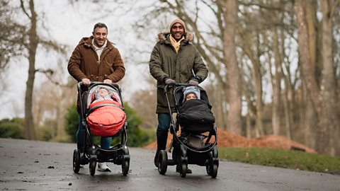 Two dads talking and pushing buggies