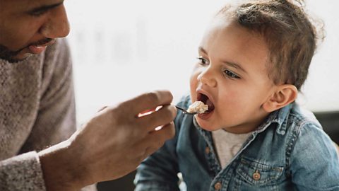 A dad feeding his baby some cereal and milk