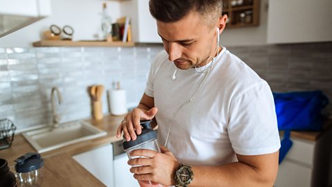 A man makes a protein shake in a kitchen