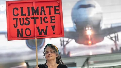 Getty Images A climate justice protester in the Munich airport last July. More Germans are factoring environmental concerns into their travel plans (Credit: Getty Images)