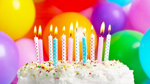 A photo of a birthday cake with lit candles on