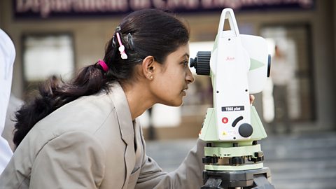 A photo of a female engineer looking through a microscope.