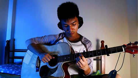 A teenage boy playing the guitar