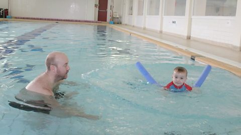 A dad and his toddler son in the swimming pool.