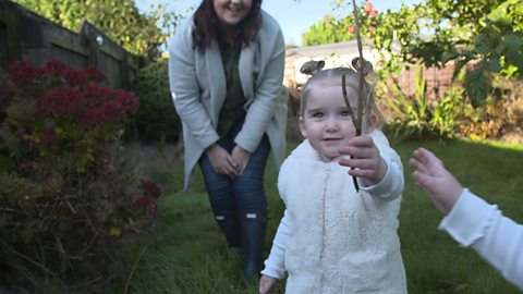 A little girl holding up a stick.