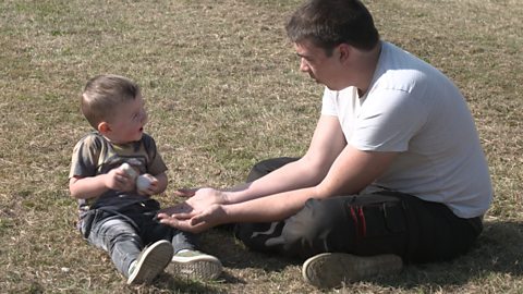 A little boy and his dad playing with pebbles.