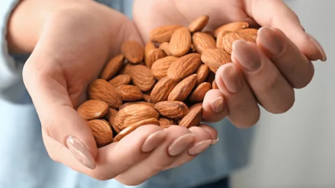 Getty Images Woman with handful of almonds (Credit: Getty Images)