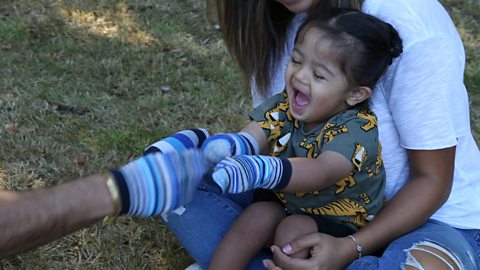 Little girl laughing whilst playing sock puppets.