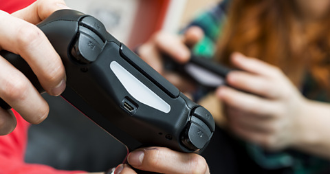 Two people's hands holding games controllers.