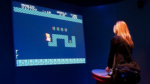 A woman playing classic super mario brothers game on a big screen