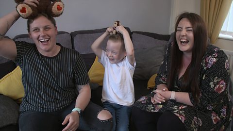 Two mums and their little boy holding teddy monkeys on their head.