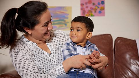 Mum smiling at toddler who is sat on her knee