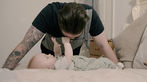 Dad leaning over his baby who is holding onto his glasses.