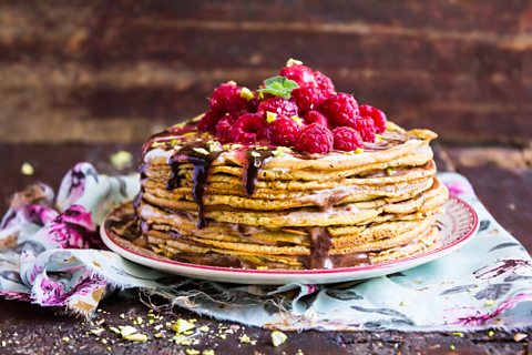 A stack of pancakes topped with red berries.