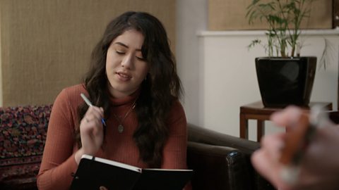 A woman playing guitar with a group writing music.