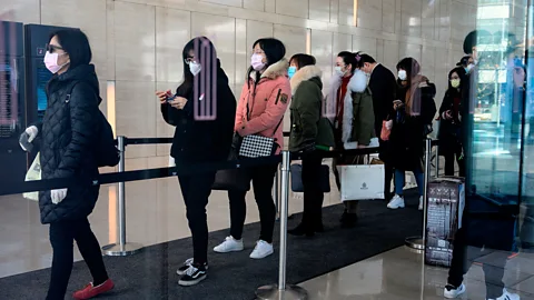 Getty Images Workers queue to enter a Shanghai office on February 10 after an extended holiday to slow the spread of the virus. Now, many such employees work remotely (Credit: Getty Images)
