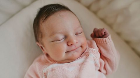 Baby in a pink jumper sleeping