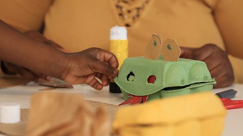 A child's hands making a monster using a cardboard egg carton.