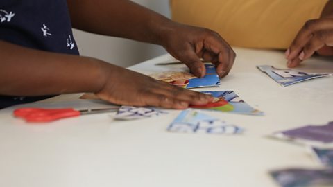 A little girl's hands piecing a cardboard jigsaw back together.