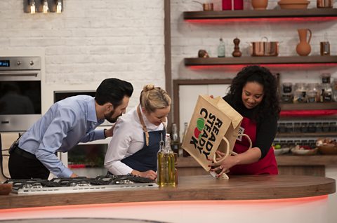 Chefs’ tips for getting creative in the kitchen Anna and Rylan look on to see what is in the bag that a contestant is emptying on the table.