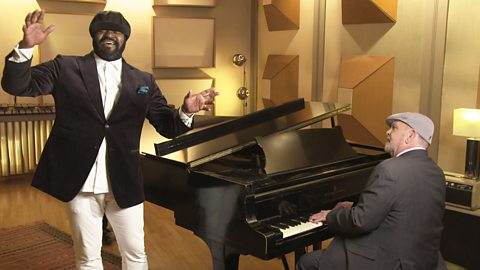 Gregory Porter singing, accompanied by Chip Crawford on piano, in a recording studio. 