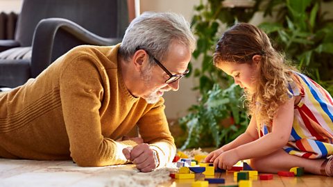 Girl building blocks with family