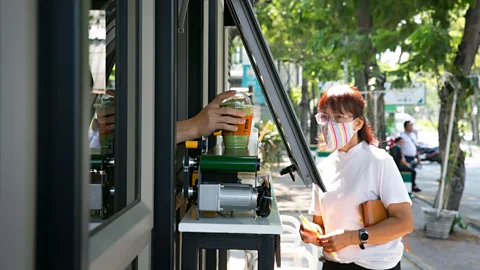 Getty Images A customer in Thailand receives her drink from a street vendor at a safe distance thanks to a conveyor belt (Credit: Getty Images)