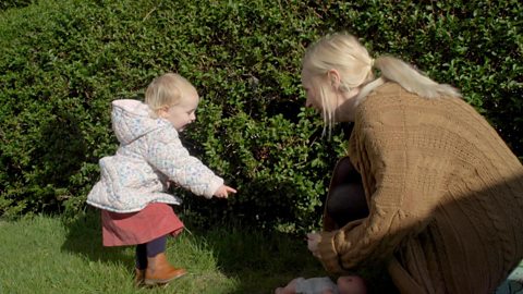 A little girl and her mum playing hide and seek.