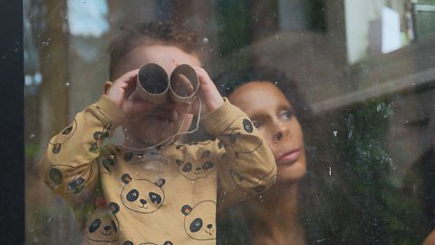 Annie Price's son Sonny looks through a pair of toilet roll tube binoculars as she looks on.