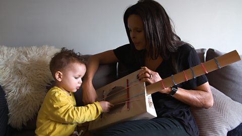 Annie Price and her son Sonny playing with a cardboard guitar.