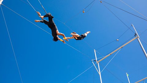 Trapeze artists flying in the blue sky.