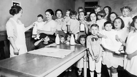 Getty Images Children and mothers receive free milk from a health station in New York’s Lower East Side (Credit: Getty Images)