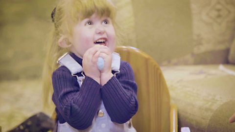 A little girl squeezing a ball of yarn.