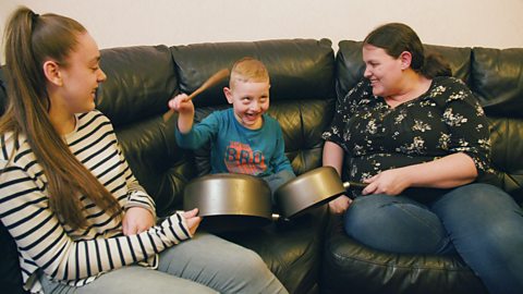 A little boy with his sister and mother drumming on some pans.