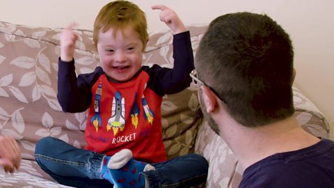 A young boy singing an action song with his dad.