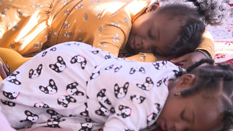 Two young girls asleep on the floor playing a game of sleeping lines.