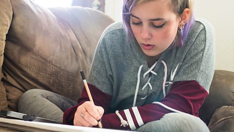 A girl sketching whilst sitting on a sofa