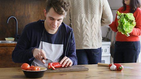 A boy cutting peppers and tomatoes