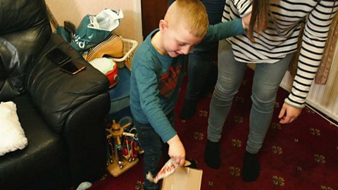 A little boy placing a cardboard box on the floor.