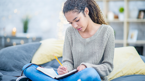 Teenage girl writing on her bed