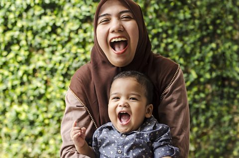 Mum and tiny son mouths open and laughing together.